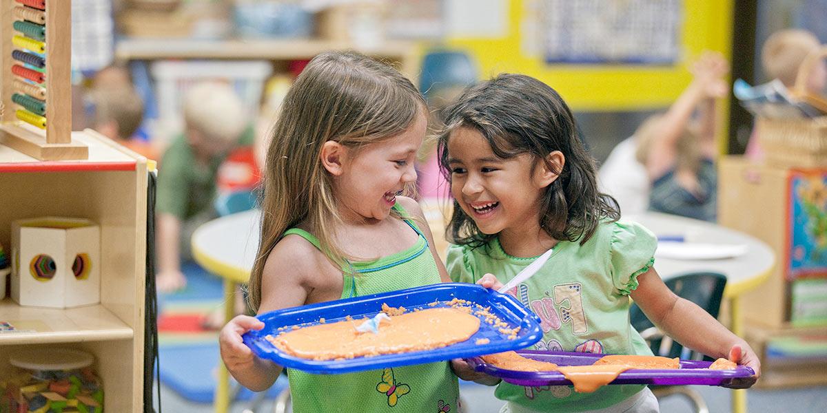 Two girls giggle together in AACC's Child Development Center.